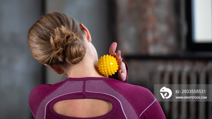 The athlete does a relaxing massage of the neck and back with the help of a prickly rubber ball.