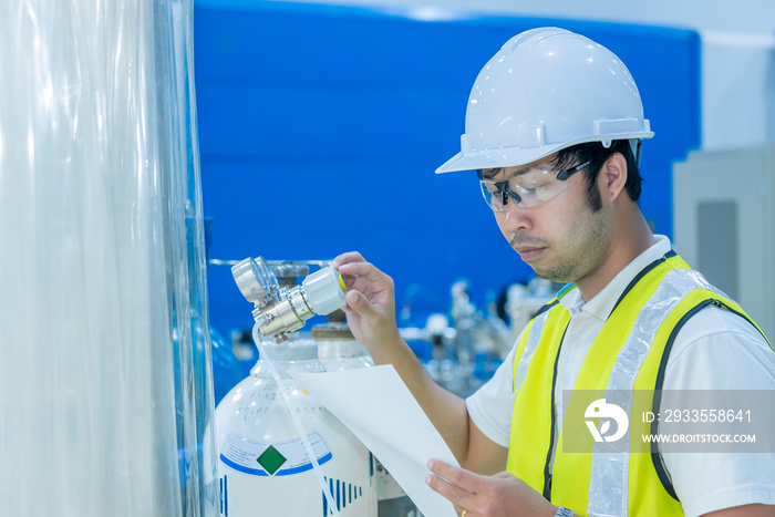 Asian engineer working at Operating hall,Thailand people wear helmet  work,He worked with diligence and patience,He checked the valve regulator at the hydrogen tank.