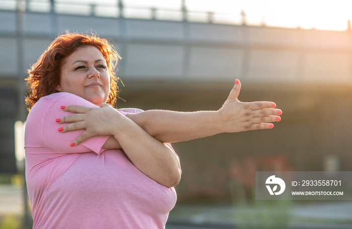 Young obese woman doing weight loss training, gymnastics exercises on a beautiful sunny day