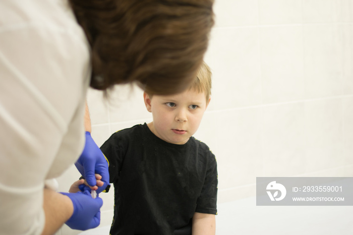 the process of drawing blood from a finger for analysis in a boy