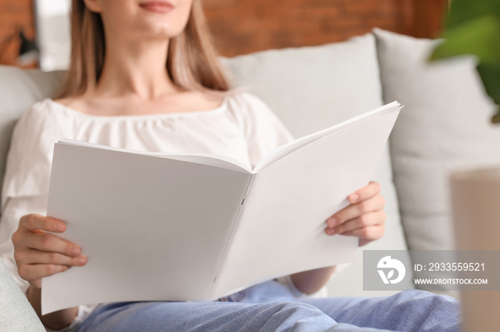 Beautiful woman reading blank magazine in living room