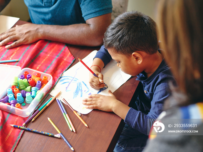 Parents and son drawing at kitchen table