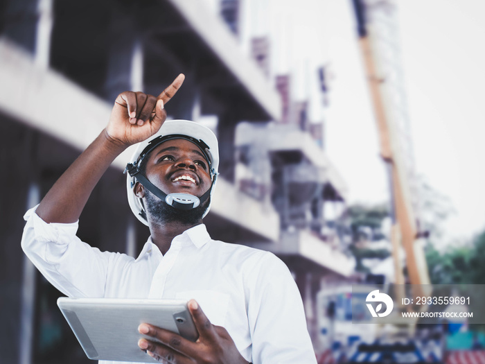 African man architect at building site. African American Engineer man use tablet device standing communication at construction building background.Concept of engineering and technology