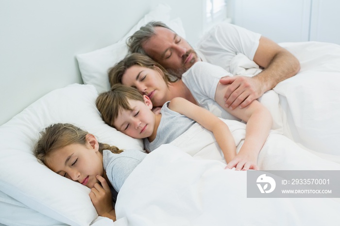 Family sleeping together in bed