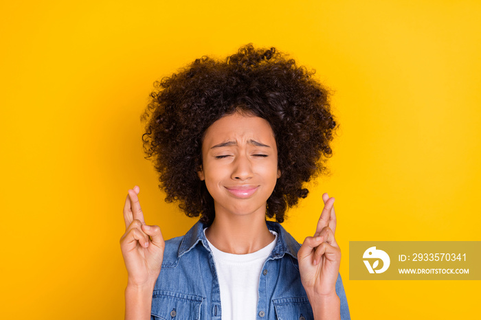 Portrait of attractive nervous teen age girl crossed fingers praying wait expect isolated over bright yellow color background