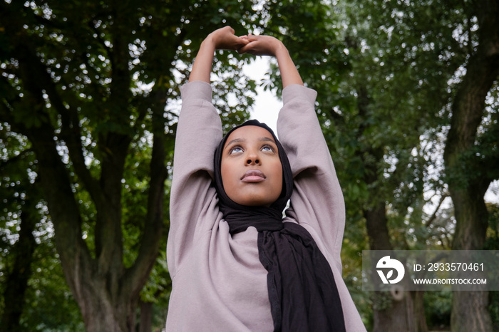 Woman in hijab stretching in park