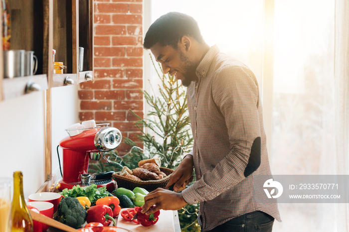 African-american man cutting bell pepper in kitchen