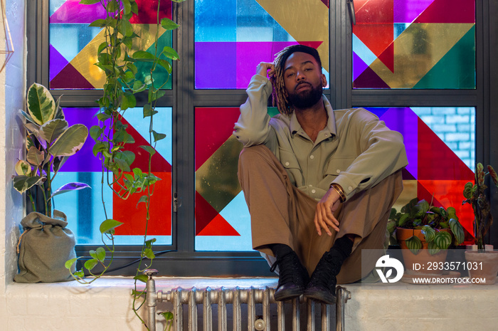 Portrait of man sitting against colorful window