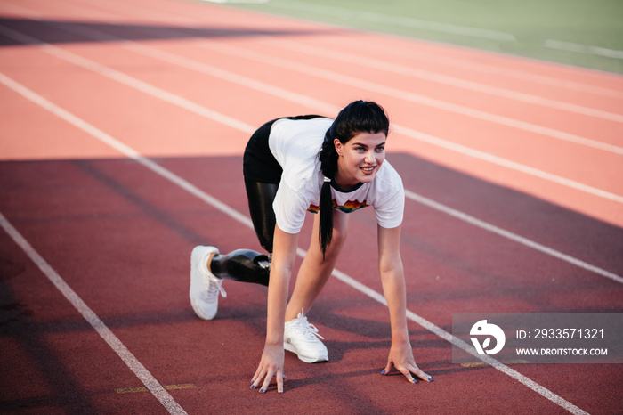 Cropped image of motivated disabled athlete woman with prosthetic leg doing stretching exercises while sitting