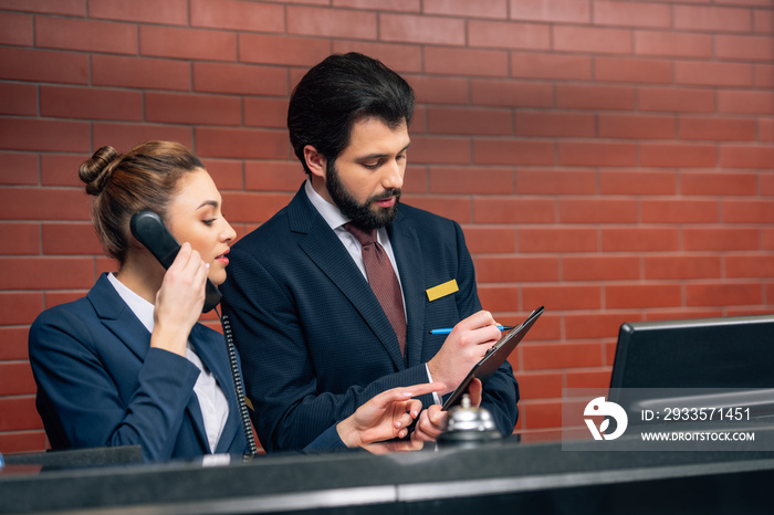 concentrated hotel receptionists receiving call from customer at workplace