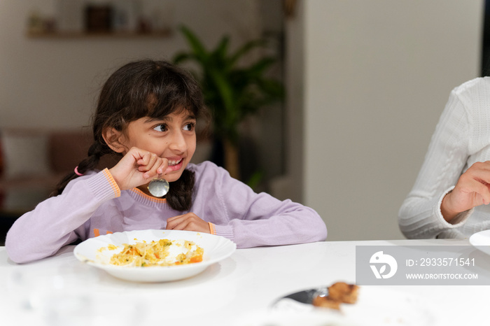 Little girl eating meal at table