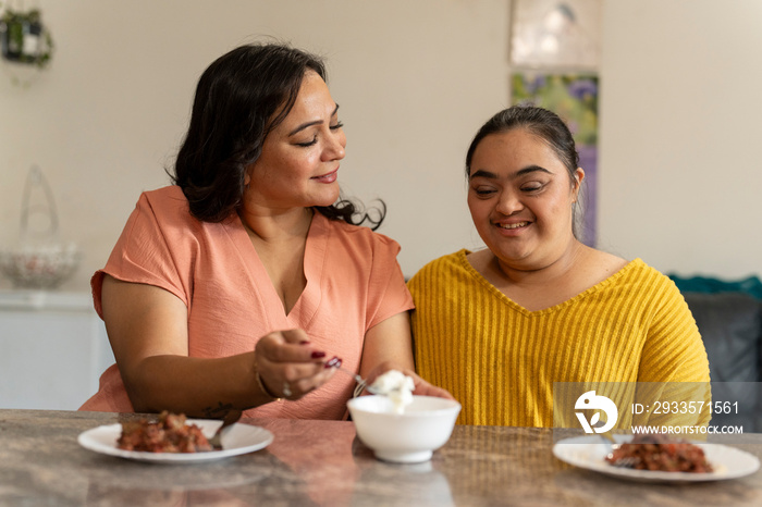 Mother eating dinner with down syndrome daughter at home