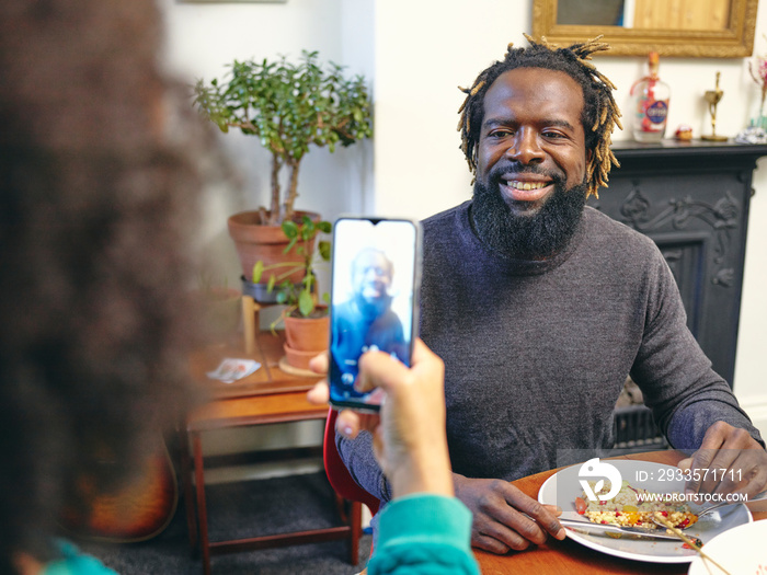 Woman taking picture of man with smart phone