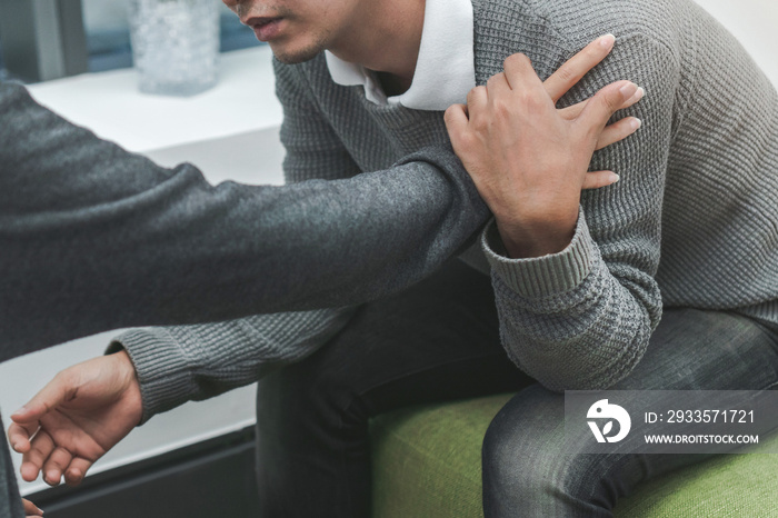 PTSD Mental health concept, Psychologist sitting and touch young depressed asian man for encouragement, Selective focus.