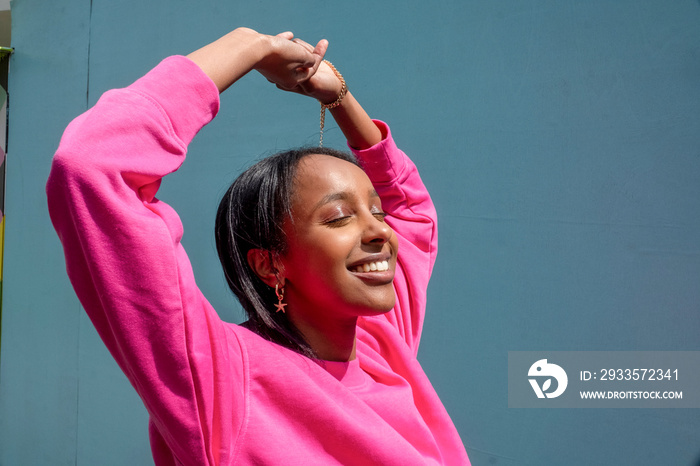 Smiling young woman holding arms up