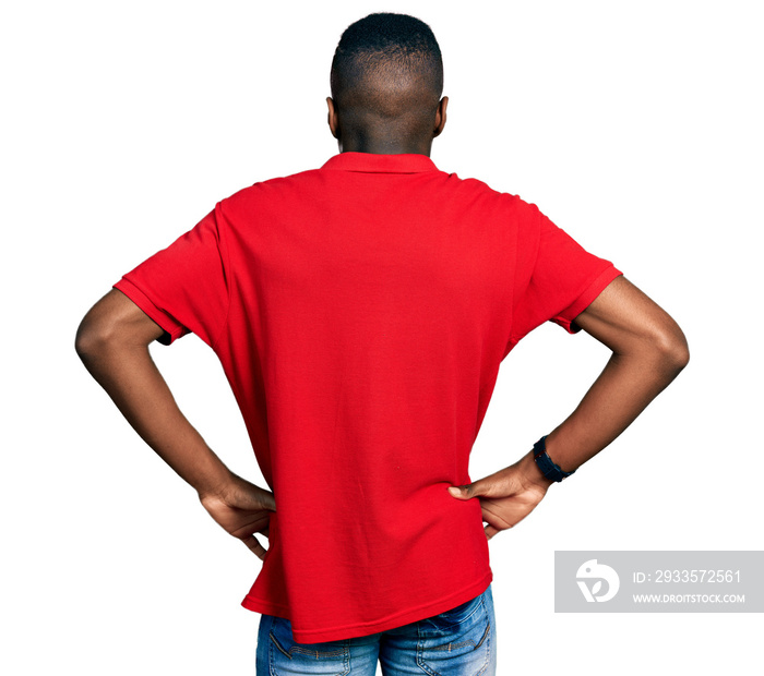 Young african american man wearing casual red t shirt standing backwards looking away with arms on body