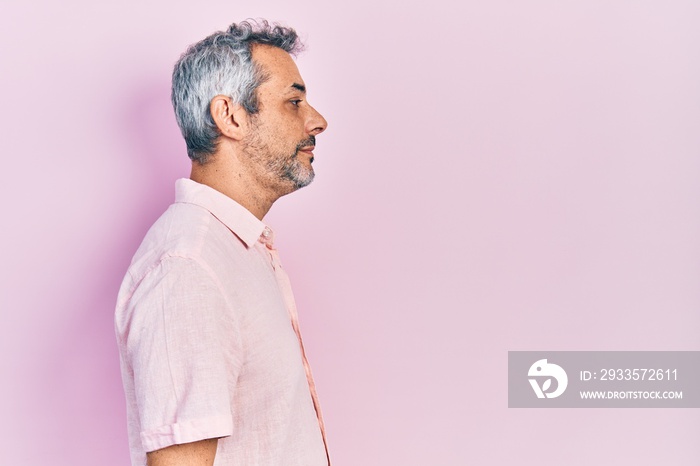 Handsome middle age man with grey hair wearing casual shirt looking to side, relax profile pose with natural face with confident smile.