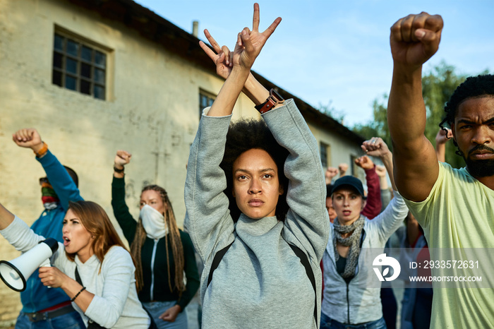 African American woman with arms above head showing peace gesture on a protest.