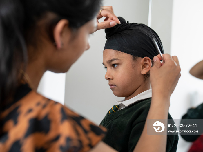 Mother wrapping traditional turban on son’s (6-7) head