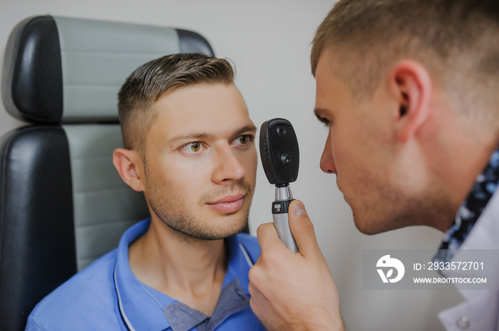 Young beautiful doctor/eye specialist/optometrist in an ophthalmologic clinic dooing to a patient eye test