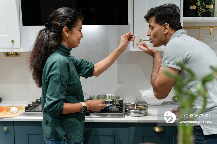 Woman giving husband dish to taste