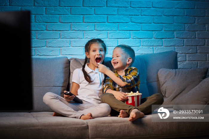 two children with remote control watching TV