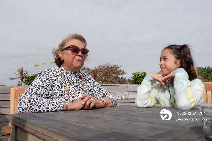 Grandmother and granddaughter sitting in outdoor restaurant