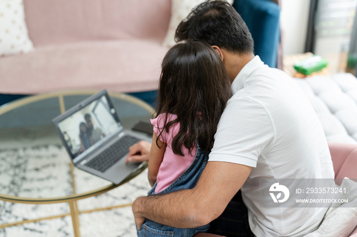 Father sitting with daughter and using laptop