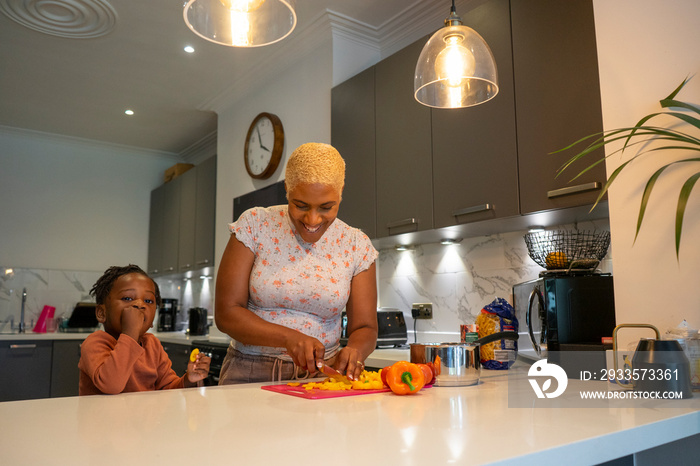 Mother and daughter (2-3) preparing food in kitchen