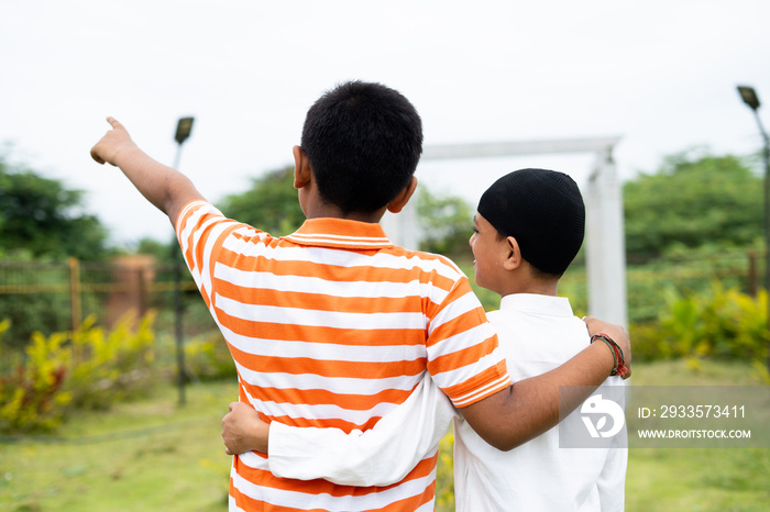 Back view of unrecognizable multiethnic friends walking by placing hands on shoulder at park - concept of diversity, friendship and communal harmony