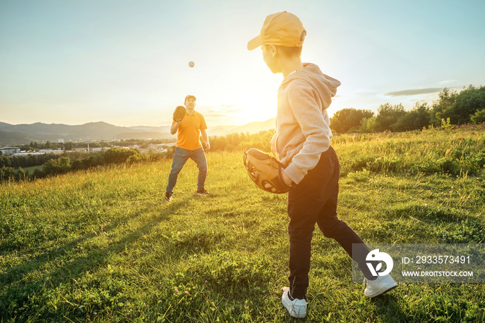 Father and son playing in baseball. Playful Man teaching Boy baseballs exercise outdoors in sunny day at public park. Family sports weekend. Father’s day.