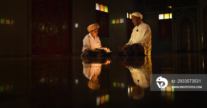 muslim boy sitting in mosque with islamic teacher learning koran book