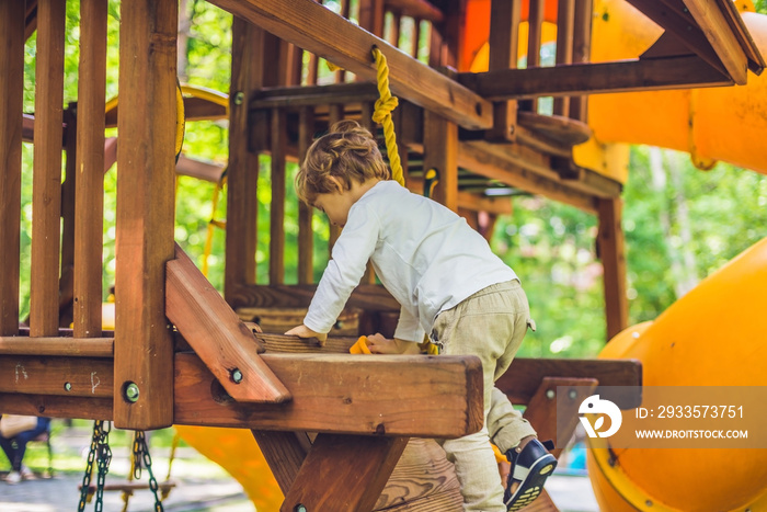 Cute little boy is playing on a wooden playground