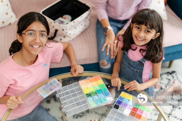 Sisters playing with beads in living room