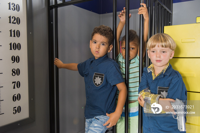 Kid protesting being arrested. Little police boy in playroom. Indoor playground for kids.