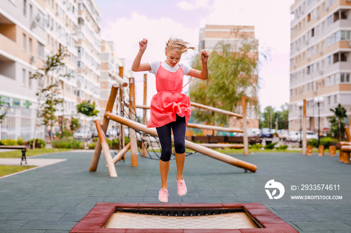 A blonde schoolgirl plays on the playground in the city’s backyard