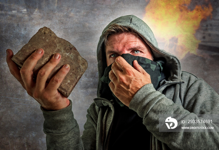 young man as ultra and radical anarchist rioter . furious antifa protester in face mask throwing brick hostile on street on demonstration in violet riot and chaos