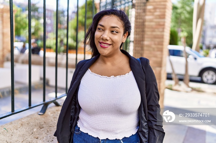 Beautiful hispanic woman smiling at the camera, walking outdoors on a sunny day. Young latina girl looking confident and happy at the city