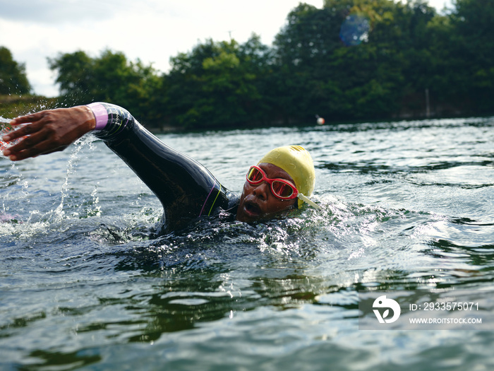 Woman in swimming cap and goggles swimming in river