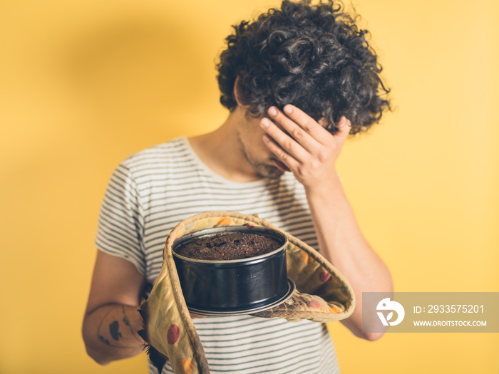 Upset young man with burnt cake