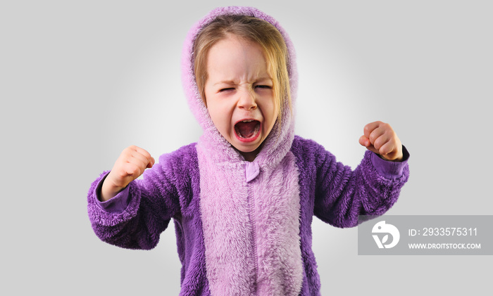 angry little toddler child furiously screaming raise hands in purple pajamas