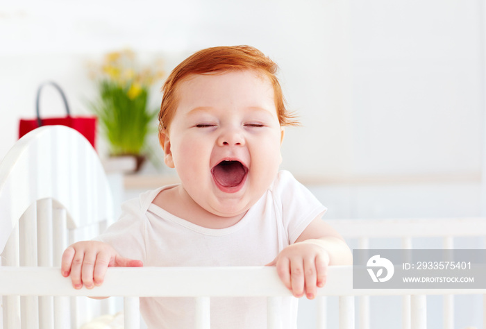 poprtait of cute happy infant baby standing in a cot at home