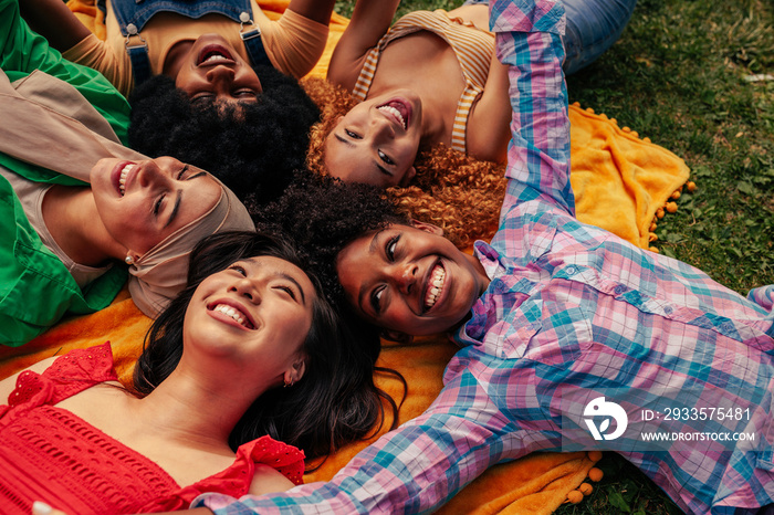 Friends lying on grass in park making circle