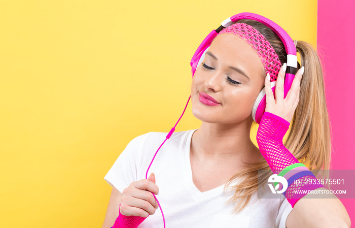 Woman in 1980’s fashion with headphones on a split yellow and pink background