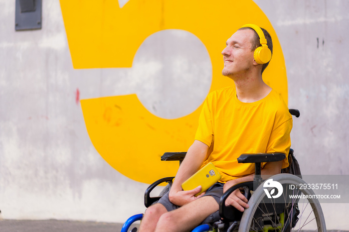 Portrait of a disabled person dressed in yellow in a wheelchair listening to music