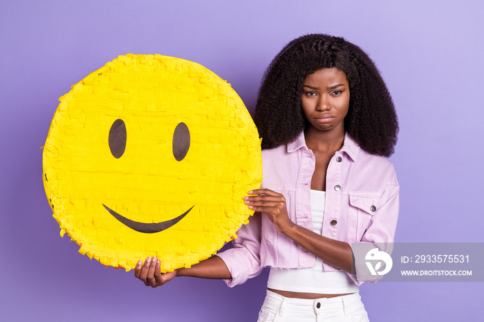 Photo of young unhappy upset sad grumpy african woman hold big yellow emoji icon isolated on purple color background