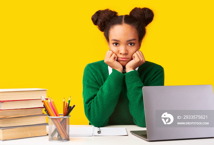 Portrait of tired black girl sitting at desk