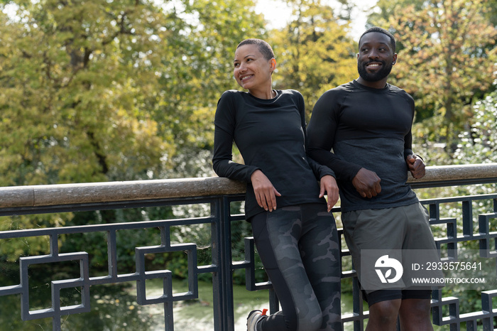 Smiling athletic man and woman relaxing in park