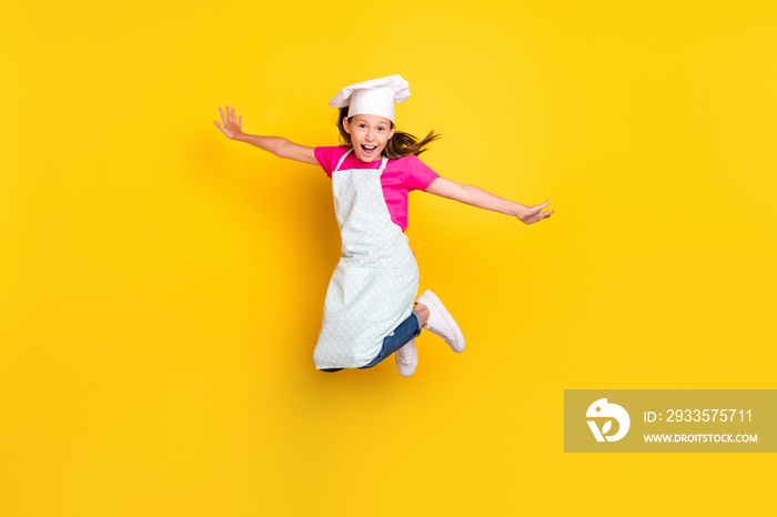 Photo of crazy active inspired carefree small girl jump wear apron cap sneakers isolated yellow color background