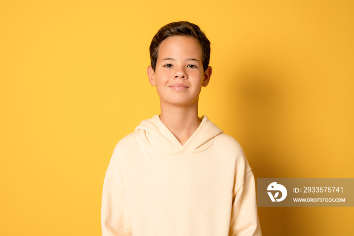 Happy young caucasian boy in casual outfit isolated over yellow background